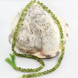 Strang aus kleinen grünen Peridotperlen um einen hellen Stein gelegt