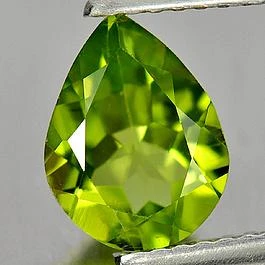 Loser Peridot in Tropfenform zwischen den Spitzen einer Pinzette